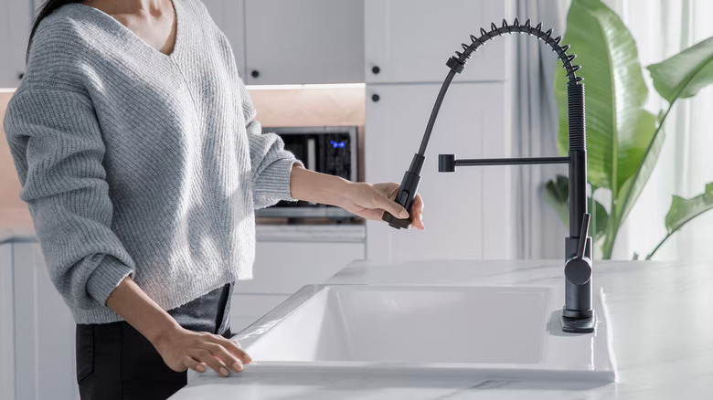 A person using a Glacier Bay kitchen faucet