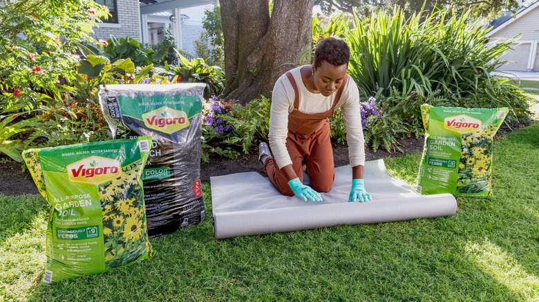 A person gardening with bags of Vigoro lawn care products on either side of them