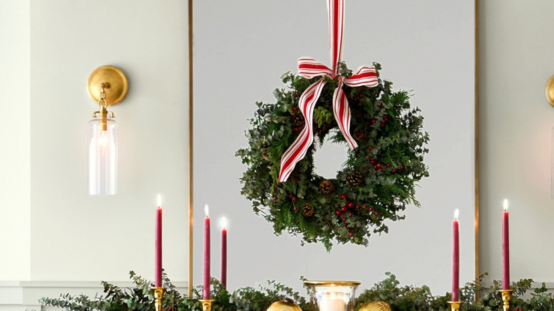 A coordinating live wreath and garland decorate a fireplace mantle
