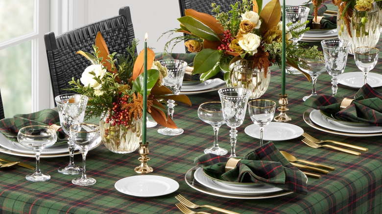 An elegant dinner table is laid with a green tartan tablecloth