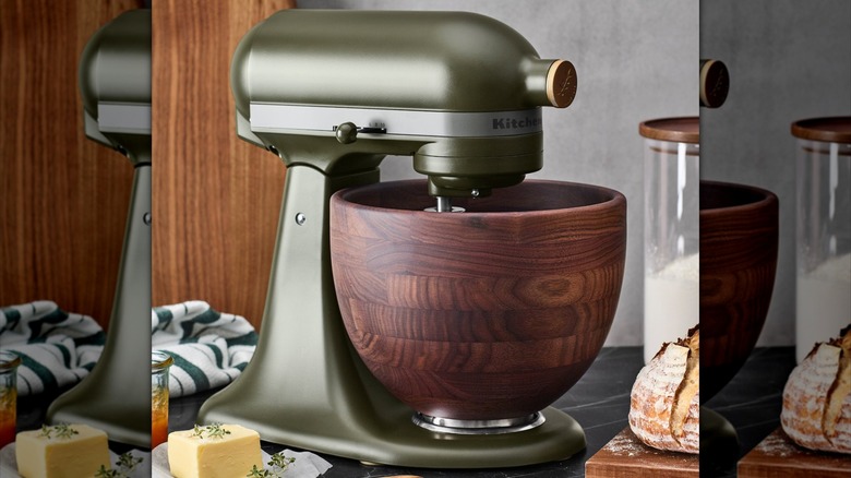 A matte green KitchenAid Stand Mixer sits on a countertop next to a loaf of bread and slab of butter