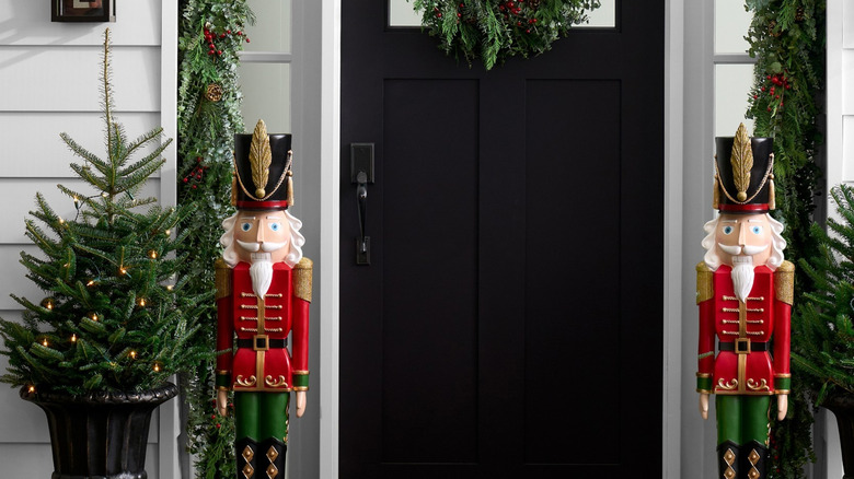 Two tall decorative Nutcrackers flank a black front door