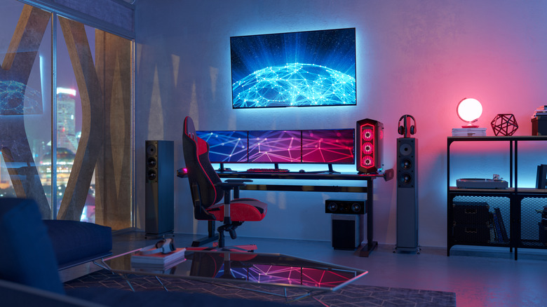 A neon lit gaming room with multiple computer screens and a large TV.