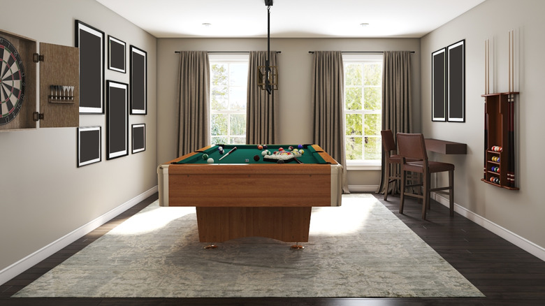 A pool table in a room with bar stools and a comfy sofa.