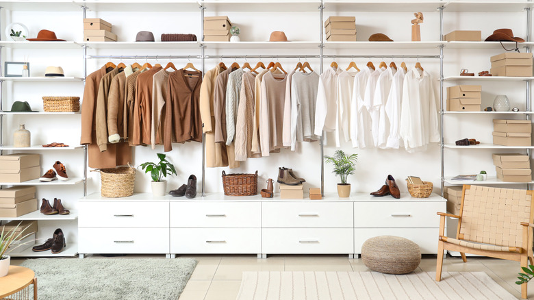 A stylish dressing room with built-in shelves and hangers filled with clothes, hats, shoes, and baskets.