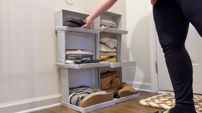 Woman putting shoes in DIY shoe storage tower made using shoe boxes