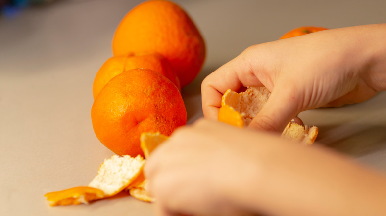 closeup child hands arranging peeled citrus