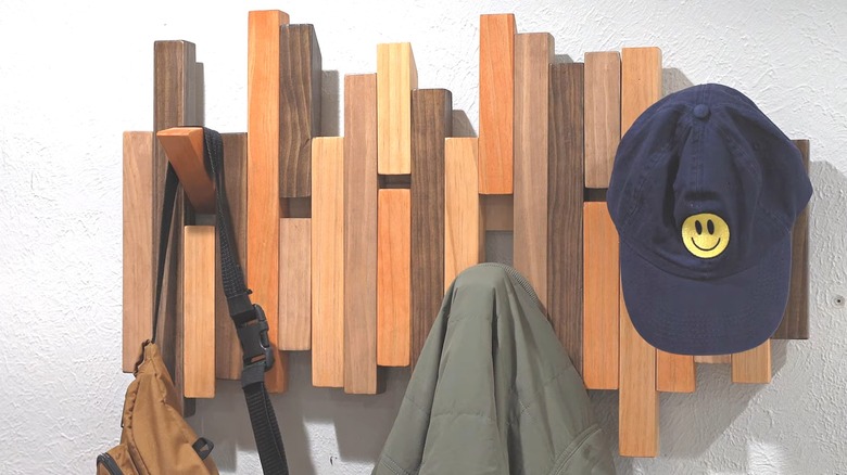 Wooden coat rack with flip-down pegs displaying a bag, coat, and hat