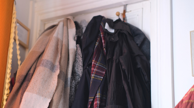 various coats messily hanging on back of door