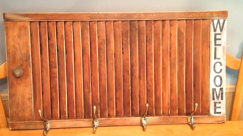 Old wooden shutter turned sidewalks with hooks attached to create a coat rack