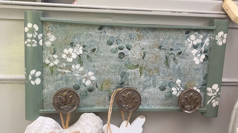 Old tray painted green with floral pattern and round, metal knobs