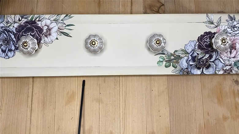Drawer front coat rack painted white with floral designs and rounded knobs