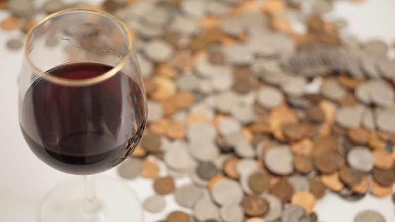 Glass of wine with pile of coins next to it