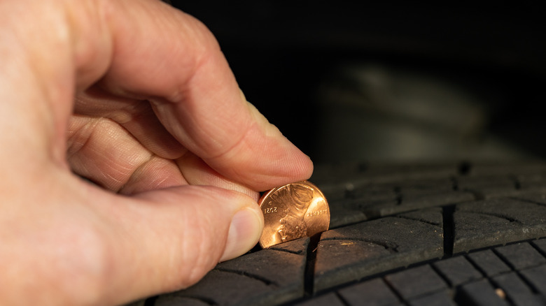 Someone using penny to check tire tread