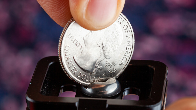 Someone using a quarter to tighten a screw