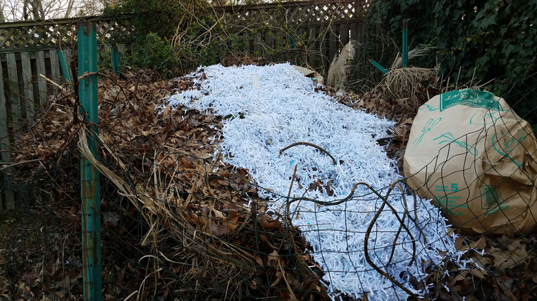 layer of white shredded paper on large compost pile