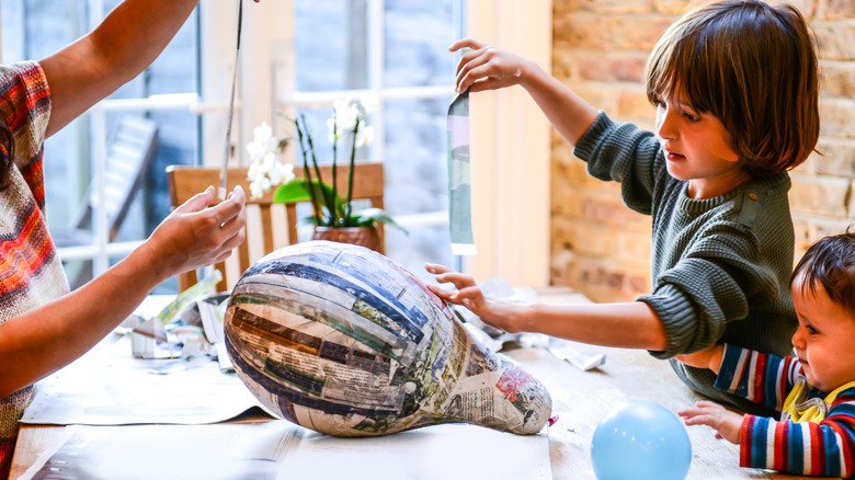 family working on a paper mache project with newspaper
