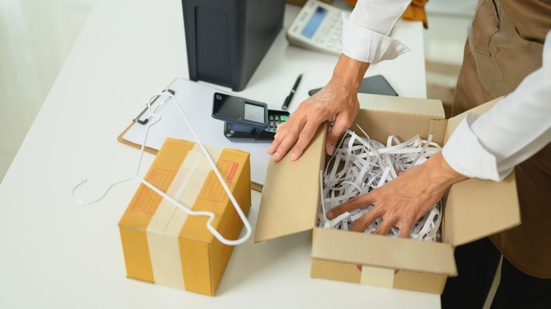 someone packing a package with shredded paper
