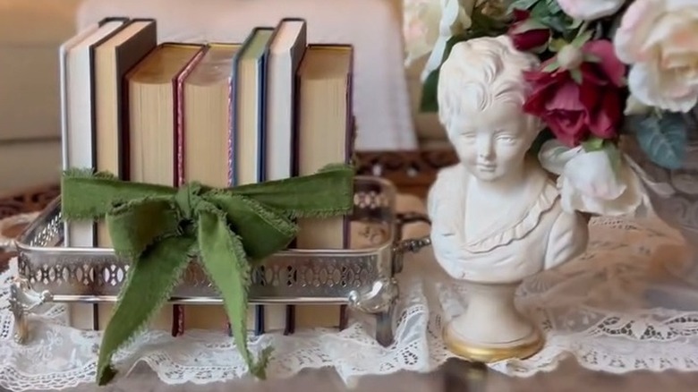 Coffee table books in a silver server beside a bust
