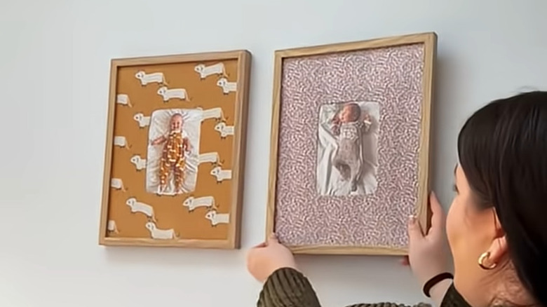 Woman hanging baby photo frames