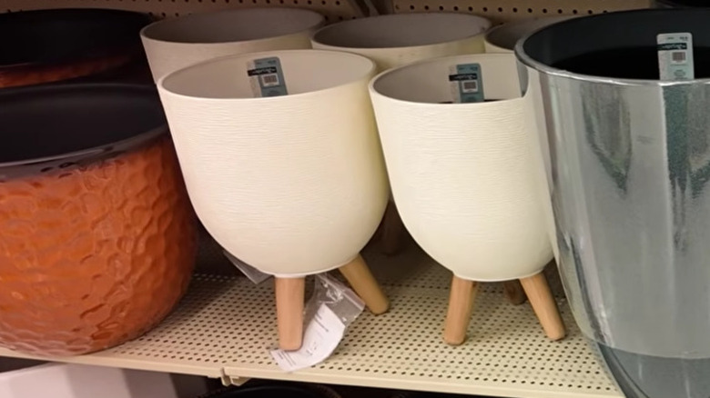 Textured white planter with wooden legs on a shelf in the Hobby Lobby floral department