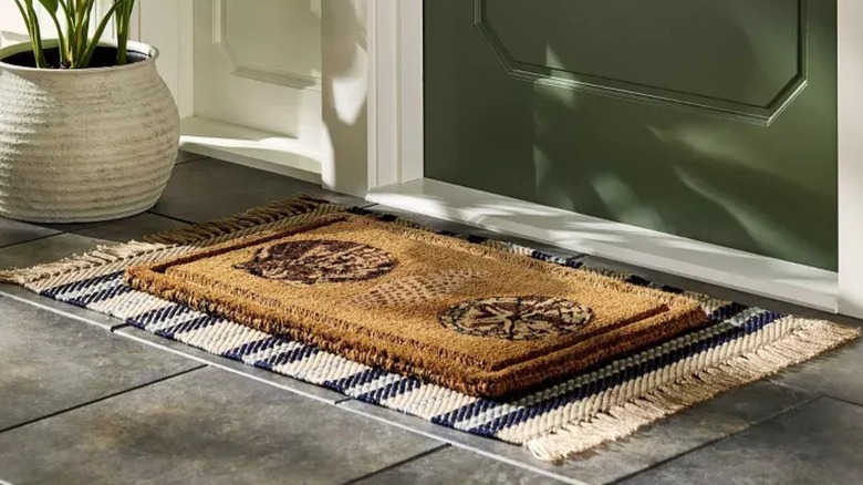 Embossed Seashells Coir Doormat in front of a green door on a tassled mat