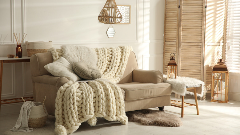 A cream and tan living room is full of cozy textiles.