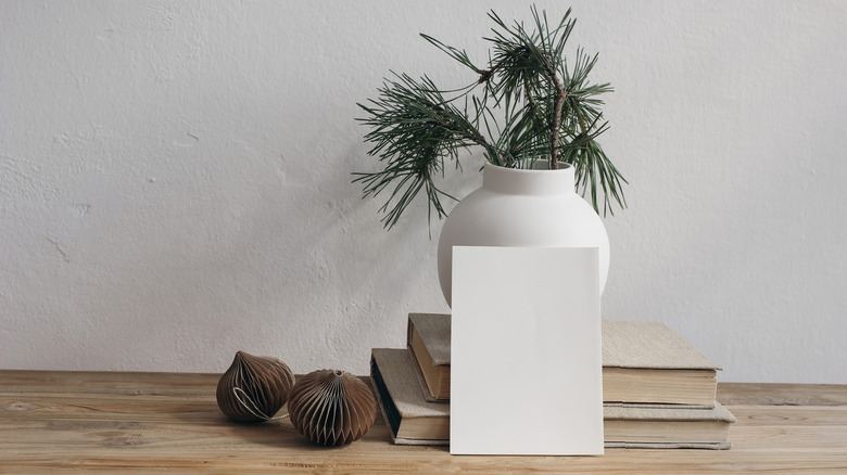 Evergreen cuttings in a vase decorate a minimalist table display.