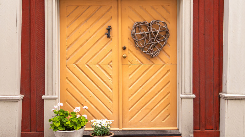 A nordic heart design made from twigs decorates a yellow wood door.