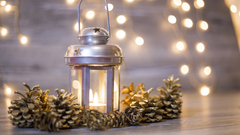 A glass and metal lantern glows with candlelight, surrounded by fairy lights.
