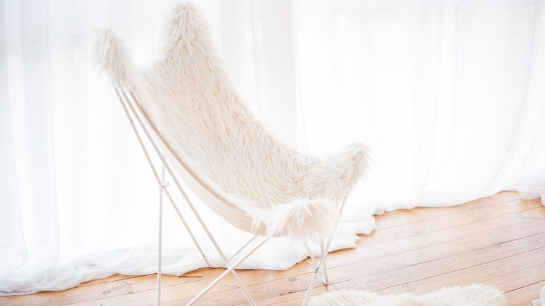 A butterfly chair with white faux-fur fabric