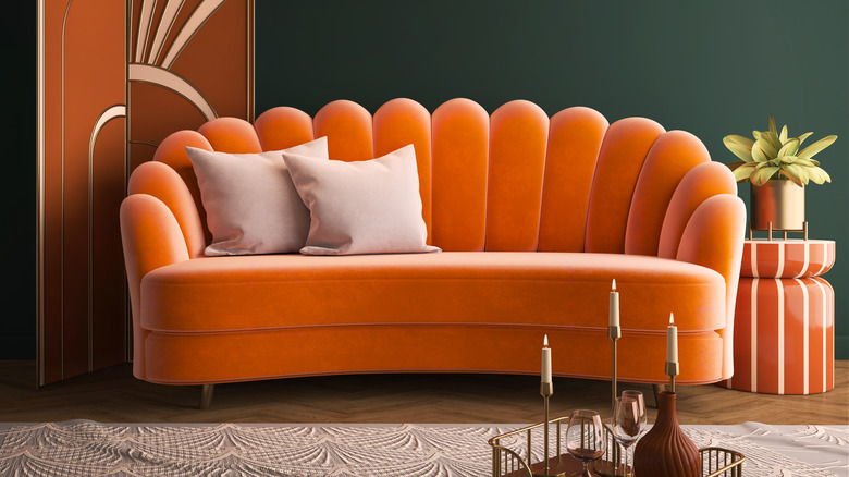An orange couch with a fluted back and curved cushions