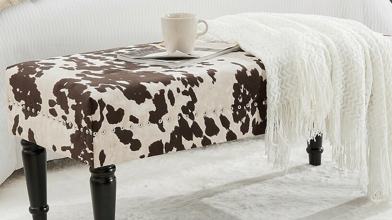 Closeup of a faux cow print bench with a blanket on top