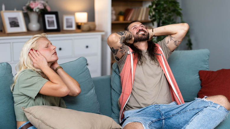 Young couple stares at the ceiling and yells because a neighbor upstairs is having a party