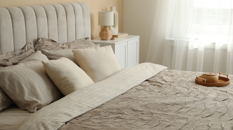 A bed with a linen bedding set in a well-lit room