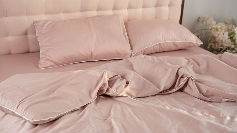 A close up to a bed with a pink silk linen set