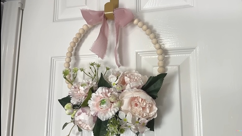 Wreath made from wooden beads, florals, and a bow hanging on a door