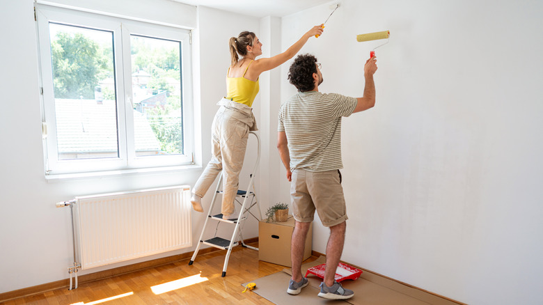 A couple painting the walls of their apartment.