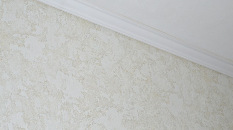 Close-up of a wall with light-colored, naturally-textured wallpaper.