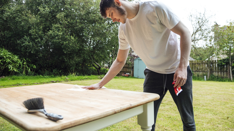 A man sanding and restoring a wooden table.