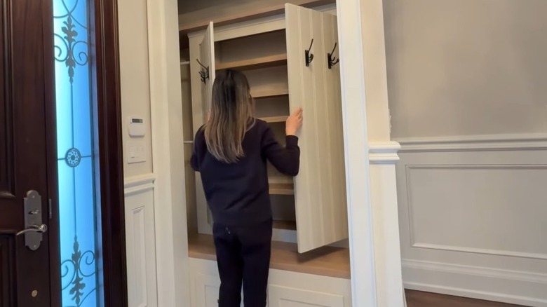 A person opens a DIY cupboard in the entryway to reveal hidden storage.