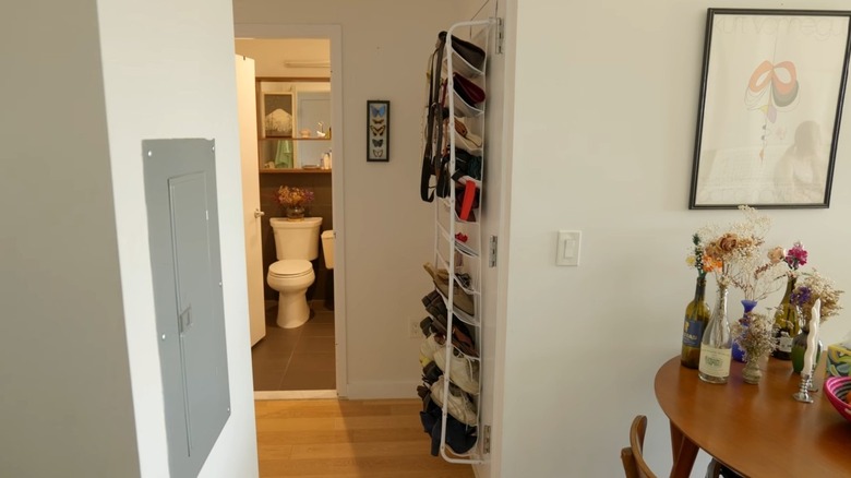A sideways view of a door organizer in a small studio apartment entryway holding bags and shoes.