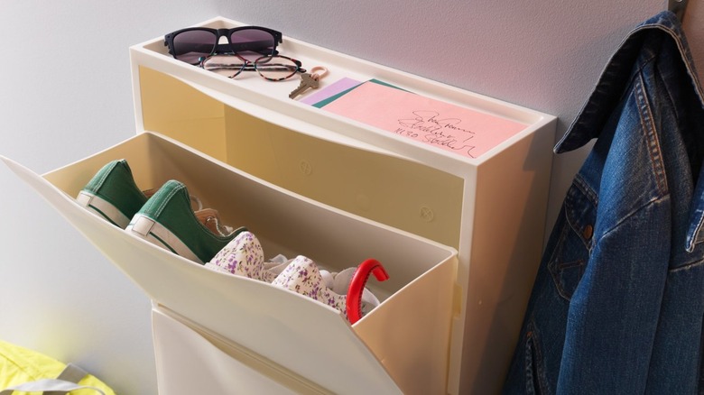 IKEA TRONES cabinets in a narrow entryway with an umbrella, jacket, shoes, and other accessories.