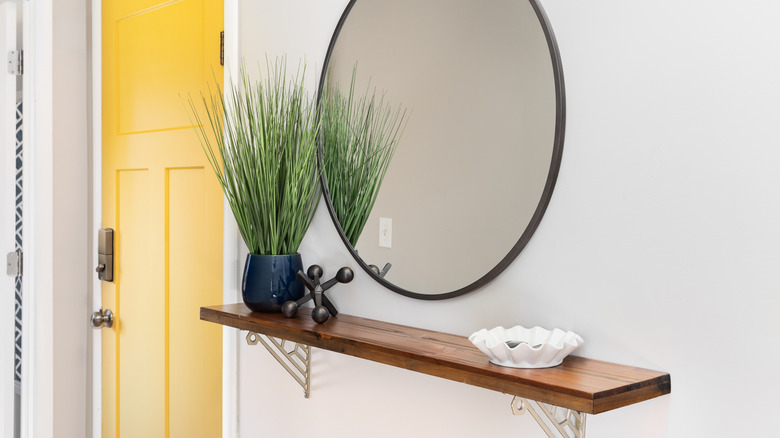 A shelf under a mirror by the front door.