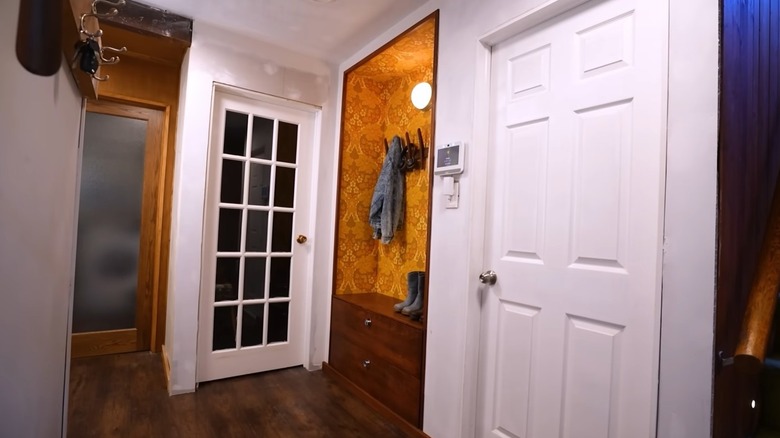 An entryway closet transformed into a stylish storage nook including a bench with storage drawers and apparel hooks.