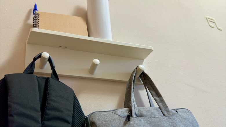 A shelf with hooks used to two backpacks, a water bottle, and a notebook