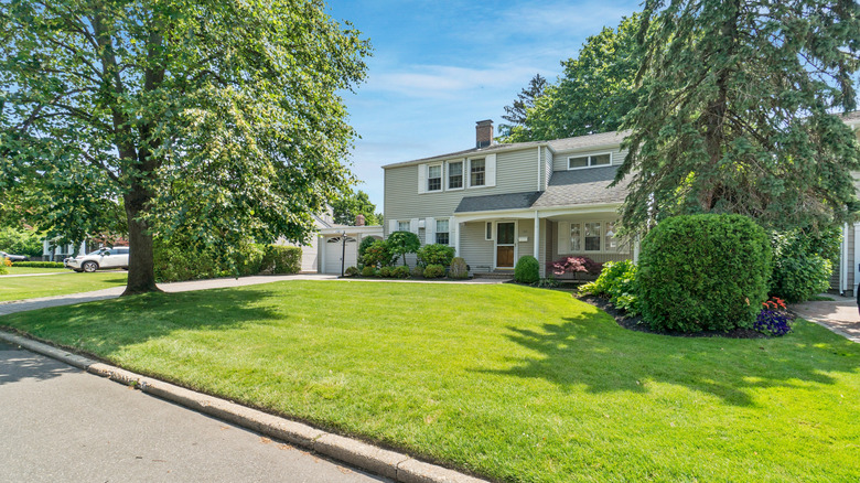 A large home with two trees in front yard.