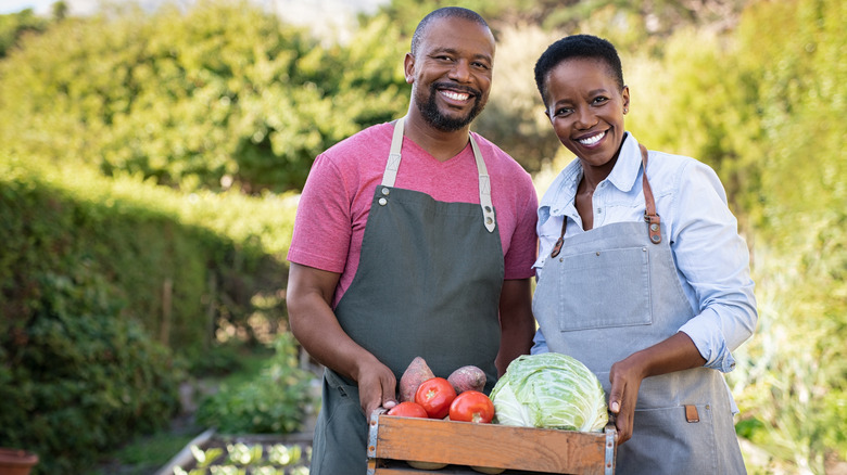 Couple holding harvested vegetables