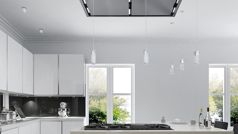 An island stove top with a flush-mounted ceiling vent above it