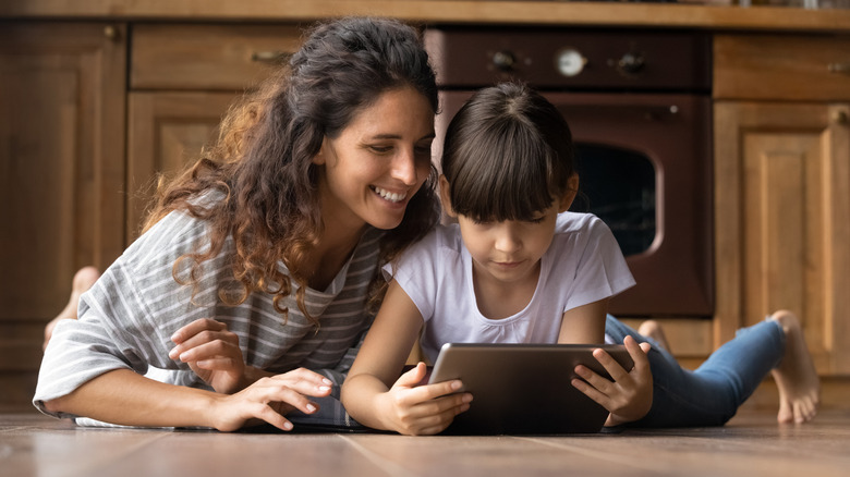 A mother and daughter lying a presumably-warm kitchen floor